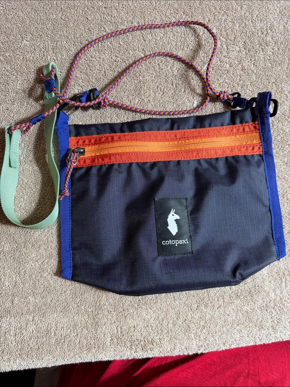 cotopaxi navy crossbody bag with orange zipper and purple trim
